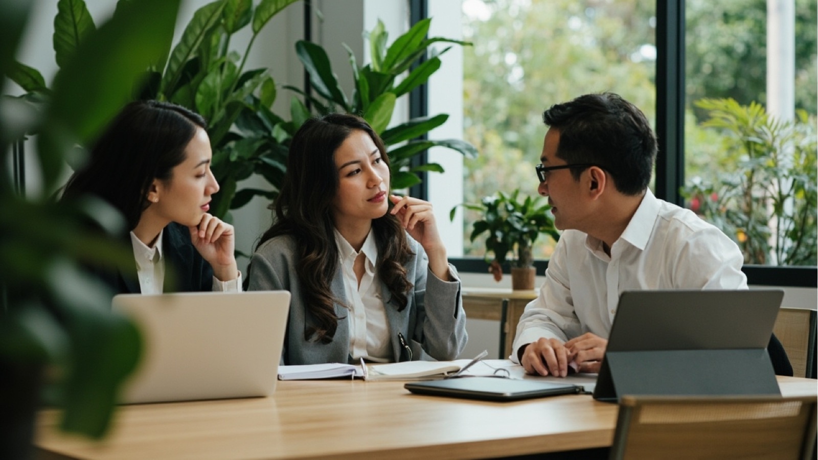 A small team collaborating around a table in a bright office with plants